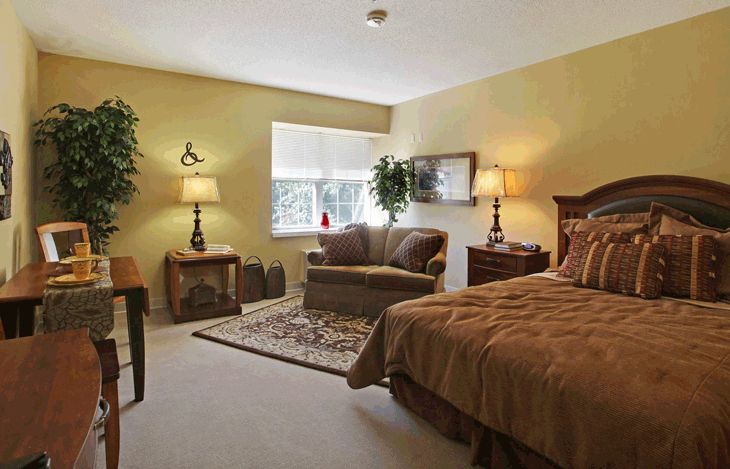 Cozy bedroom with a bed, seating area, and soft lighting.