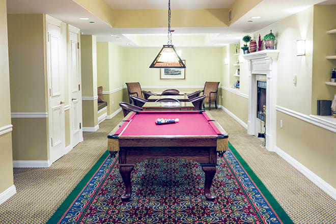 A cozy game room featuring a pool table, elegant lighting, and a fireplace.