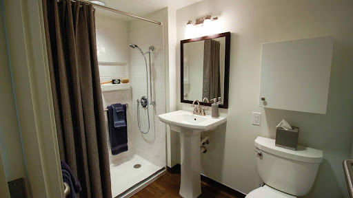 A modern bathroom featuring a shower, sink, and toilet.