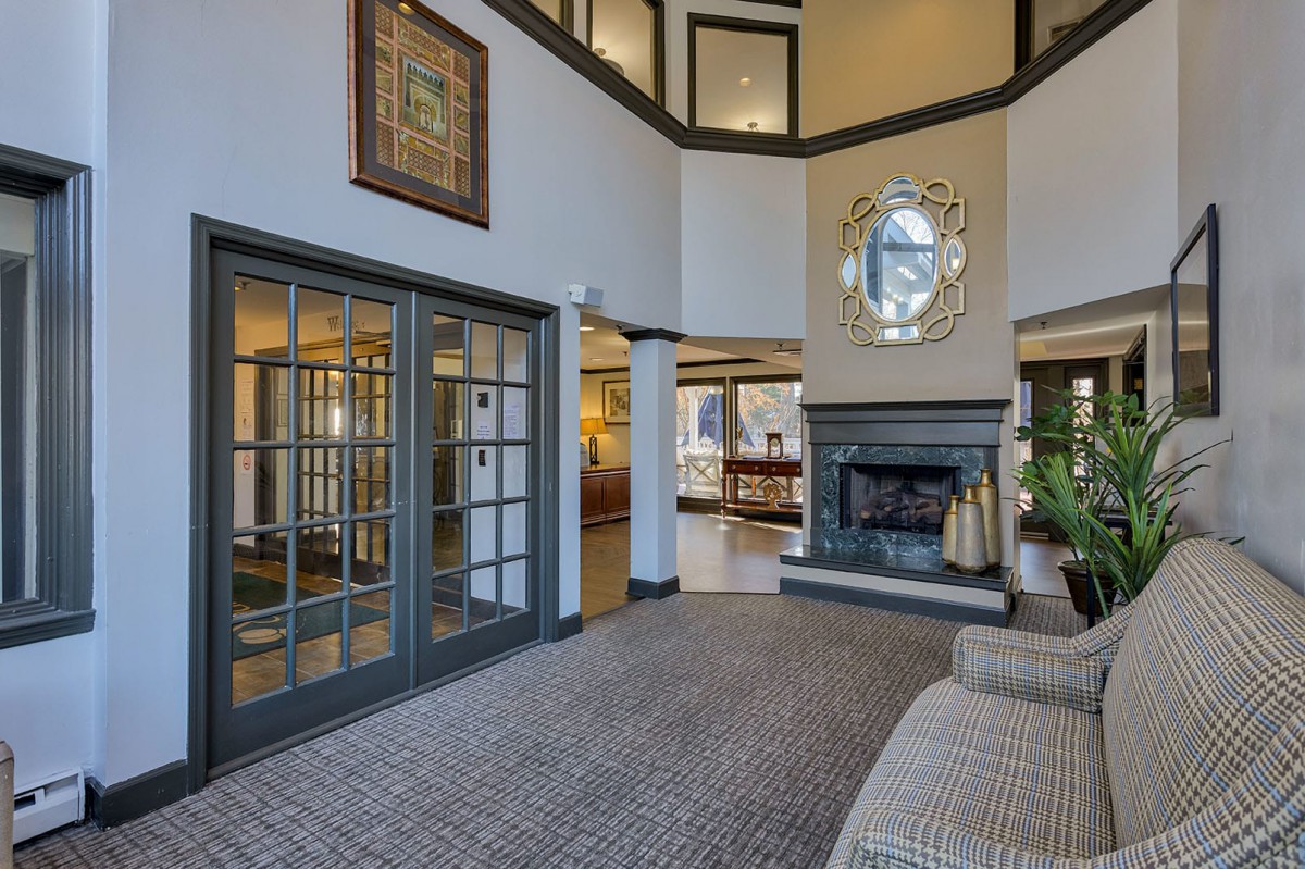 A modern two-story living room featuring a central fireplace, large windows, and elegant interior design.
