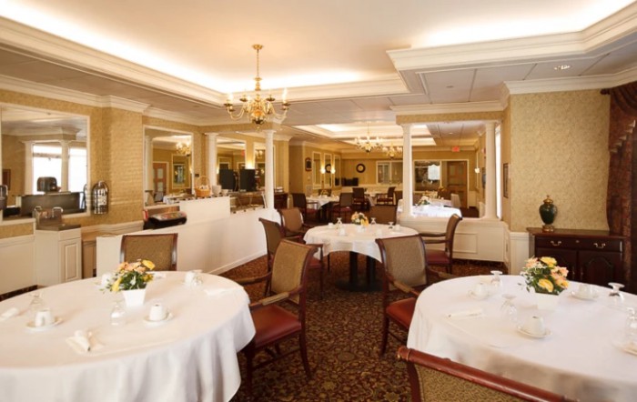 An elegant dining room with round tables and classic chandeliers.