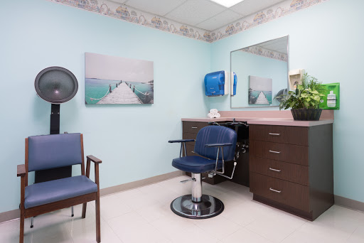 A cozy salon setup featuring a styling chair, a mirror, and a calming blue wall.