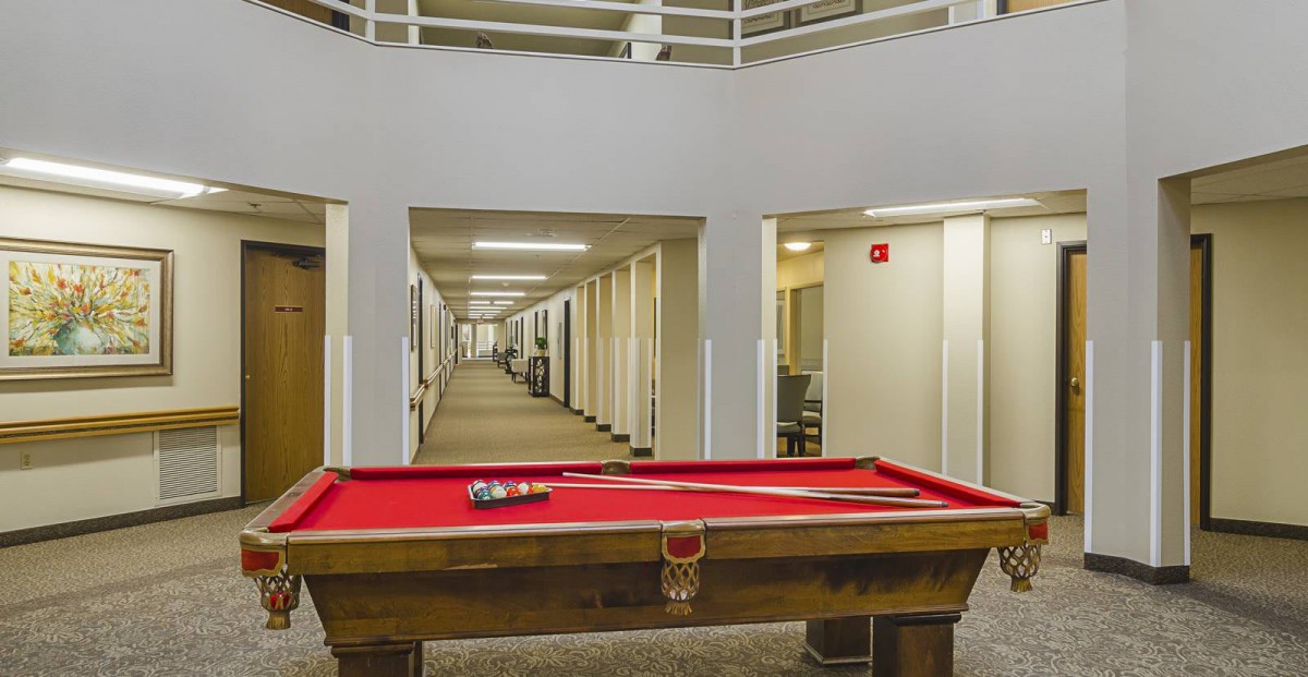 A red-felt pool table situated in a hallway of an office building.
