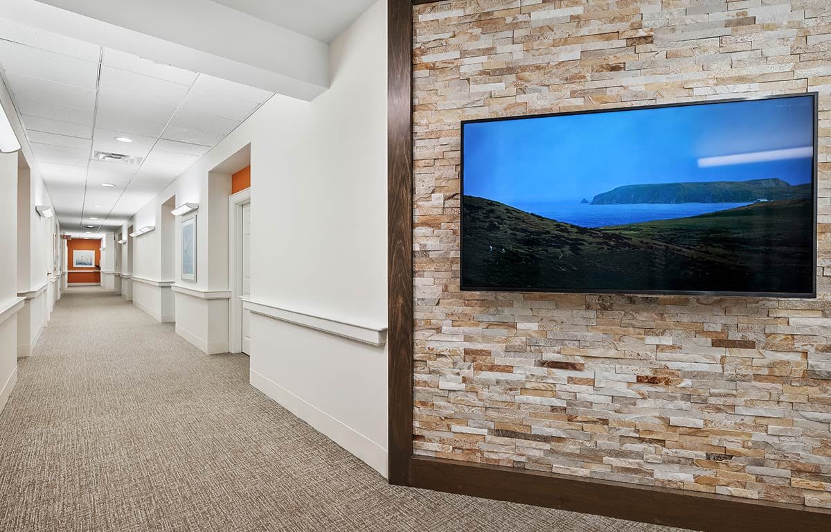 A modern hallway featuring a mounted television on a stylish stone accent wall.