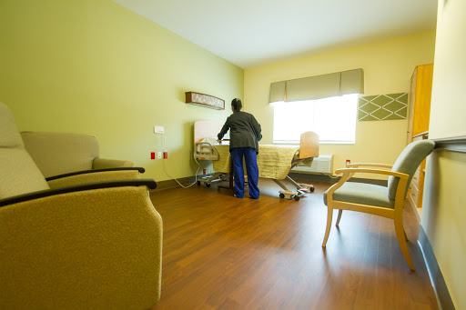 A nurse attends to medical equipment in a patient room, characterized by a calm and clean interior.
