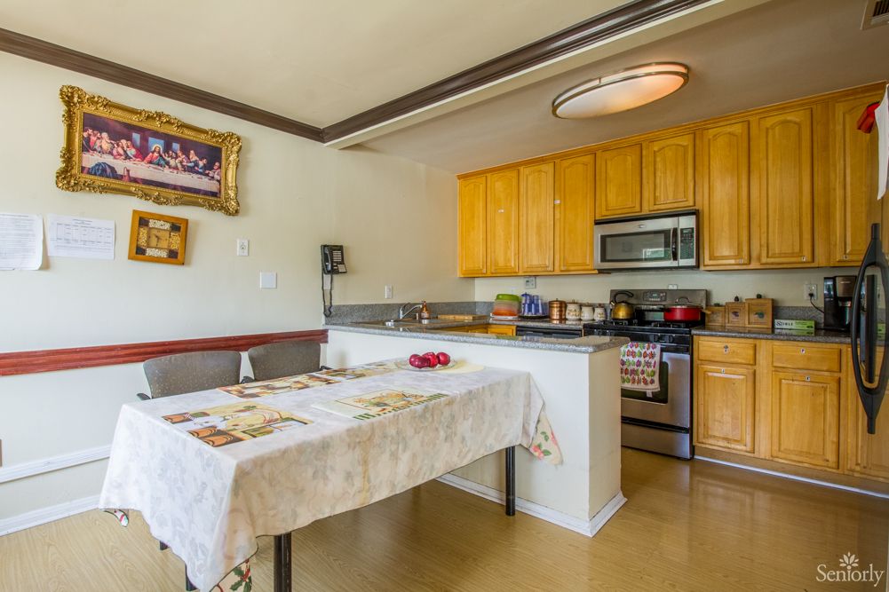 A cozy kitchen and dining area featuring wooden cabinets, stainless steel appliances, and a table with a cloth.
