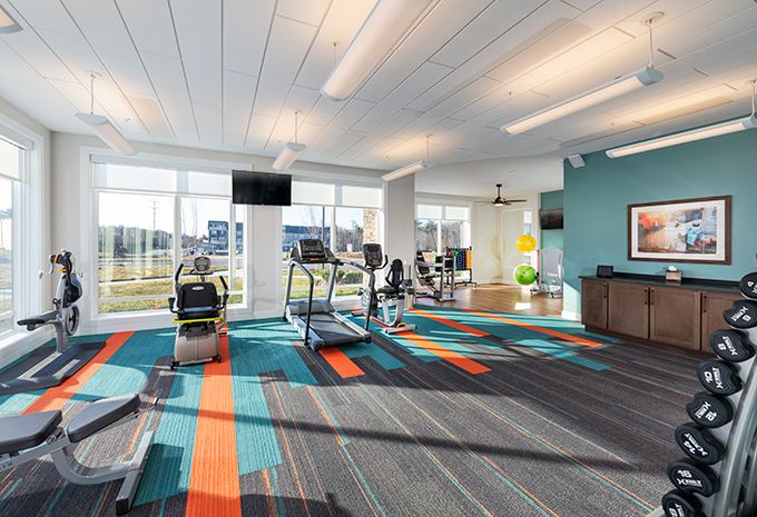 A modern gym with various exercise equipment and bright lighting.