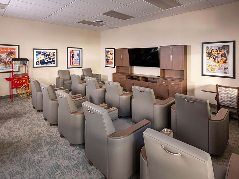 A cozy theater room with leather seating and a large television for home entertainment.