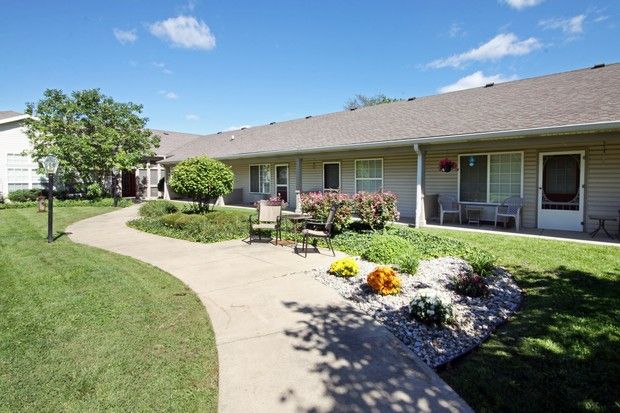 A scenic view of a single-story building with a landscaped garden and pathway on a sunny day.