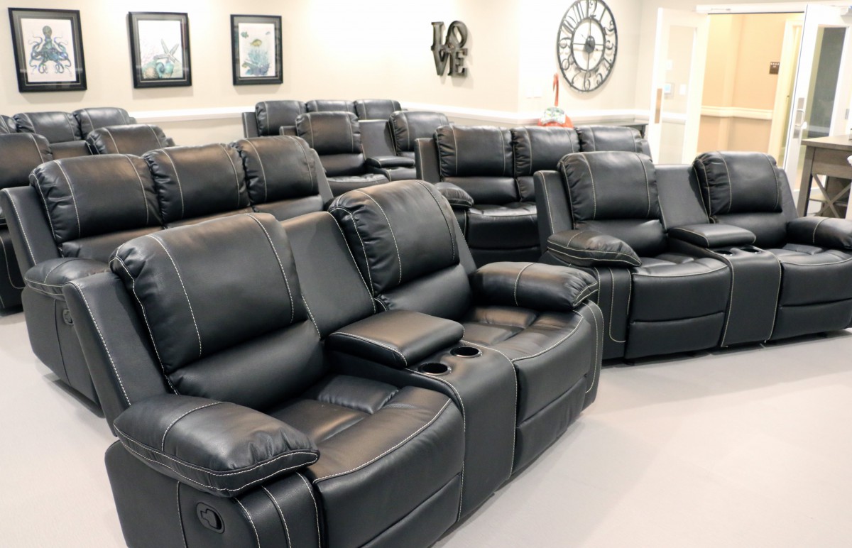 A luxurious home theater with rows of black leather recliner seats.