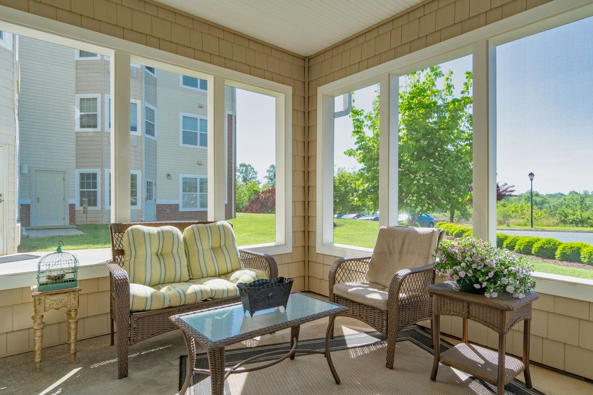 A bright sunroom with comfortable seating and large windows letting in natural light.