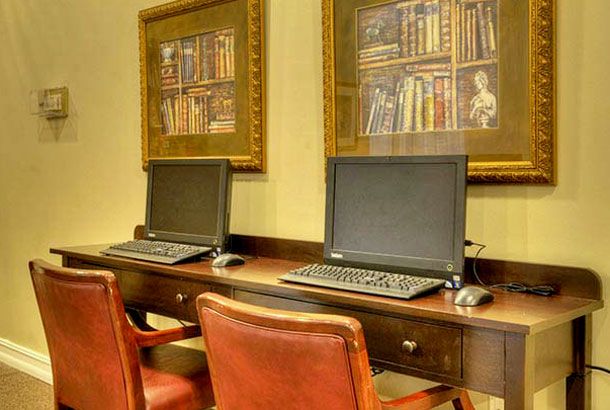 Two computers set up on a wooden desk in an office space.