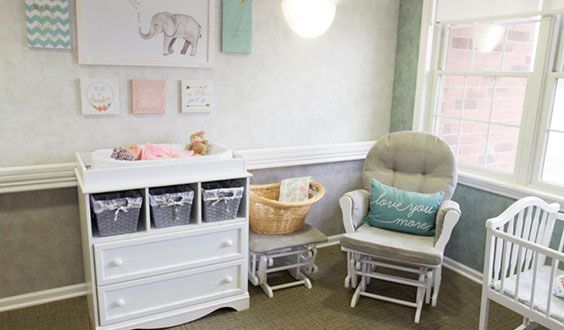 A cozy nursery featuring a rocking chair, dresser with storage baskets, and soft decor.