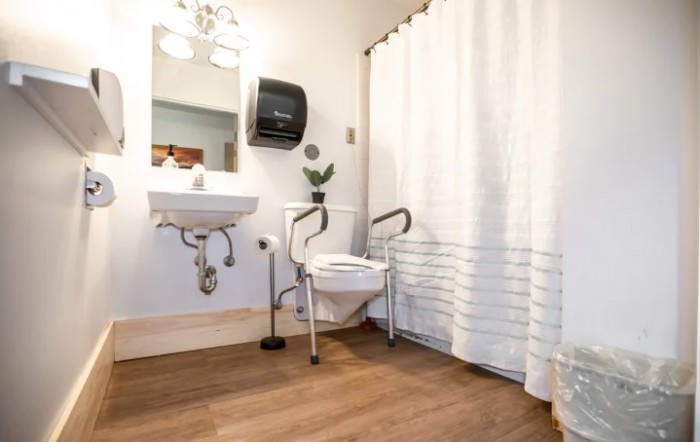 An accessible bathroom equipped with a toilet safety frame and a wall-mounted sink.
