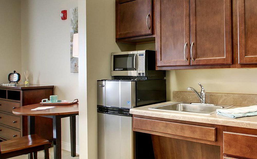 A compact kitchen area featuring a microwave, sink, and wooden cabinets.