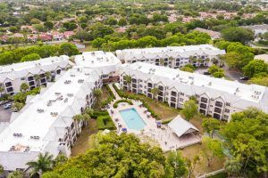 Aerial view of a residential apartment complex with a central swimming pool surrounded by greenery.