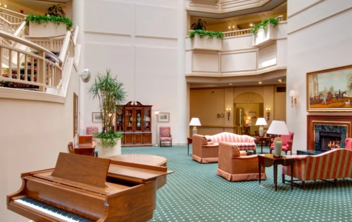 Spacious hotel lobby with elegant furniture and a grand piano.