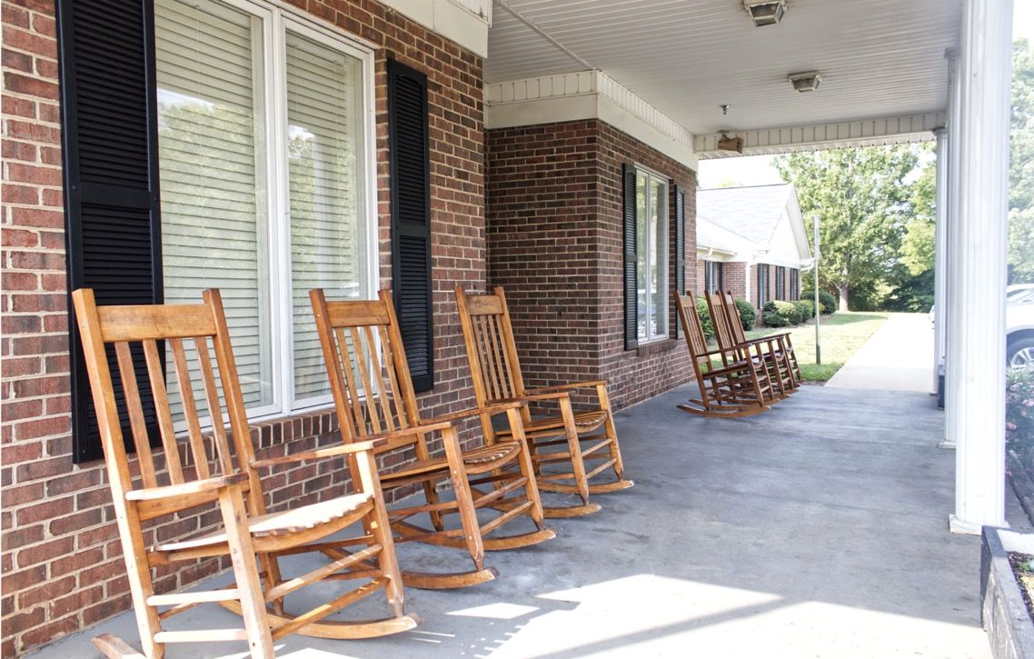 A row of wooden rocking chairs on a brick porch.