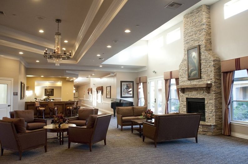 A spacious and elegantly designed lounge area featuring comfortable seating, a fireplace, and a piano.
