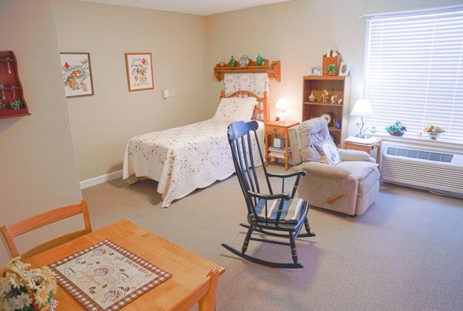 A cozy bedroom with a single bed, rocking chair, and bookshelf.
