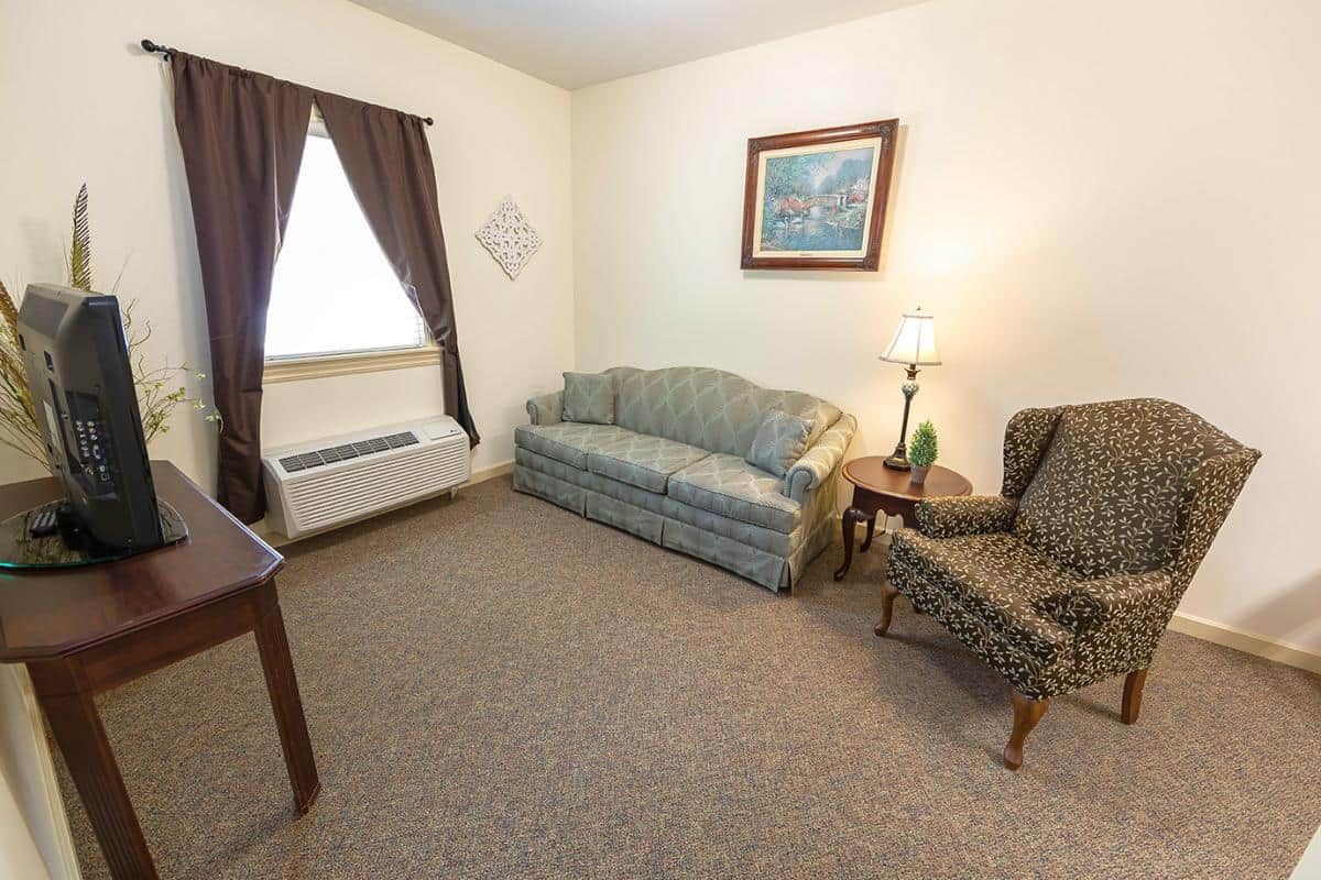 A cozy living room with a sofa, armchair, and lamp.