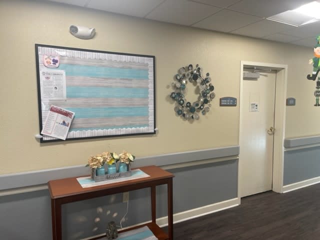 A hallway with a bulletin board and decorative items.