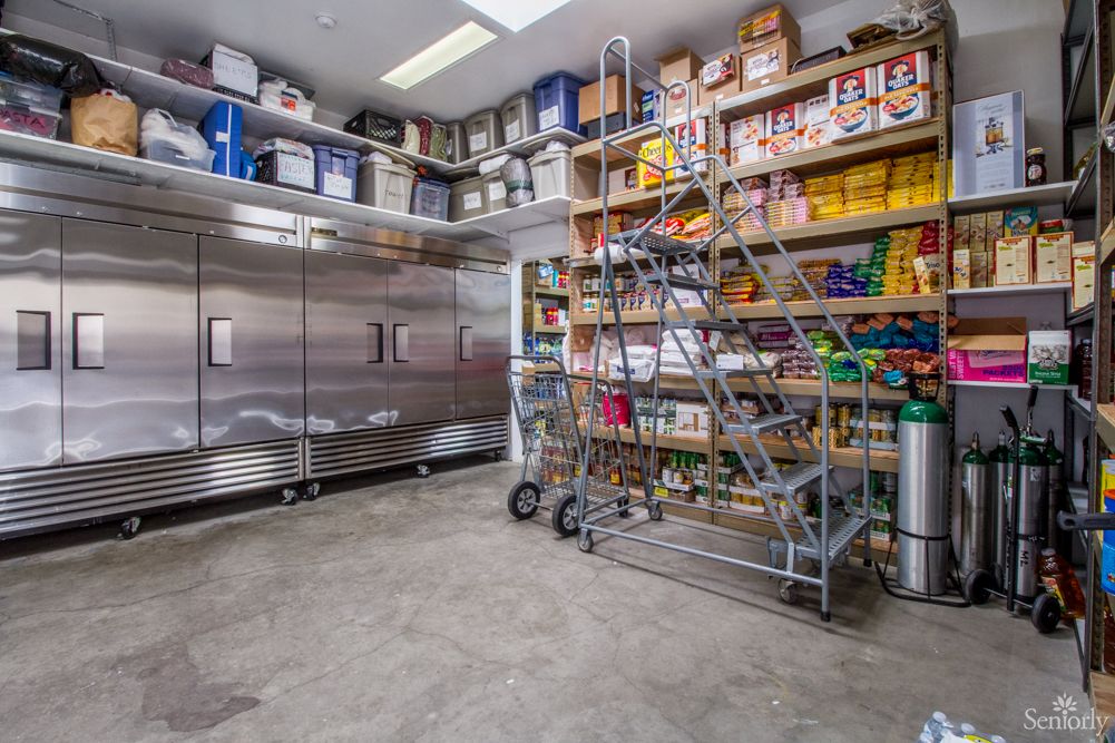 A well-organized storage room with shelves stocked with various items and an industrial refrigerator.