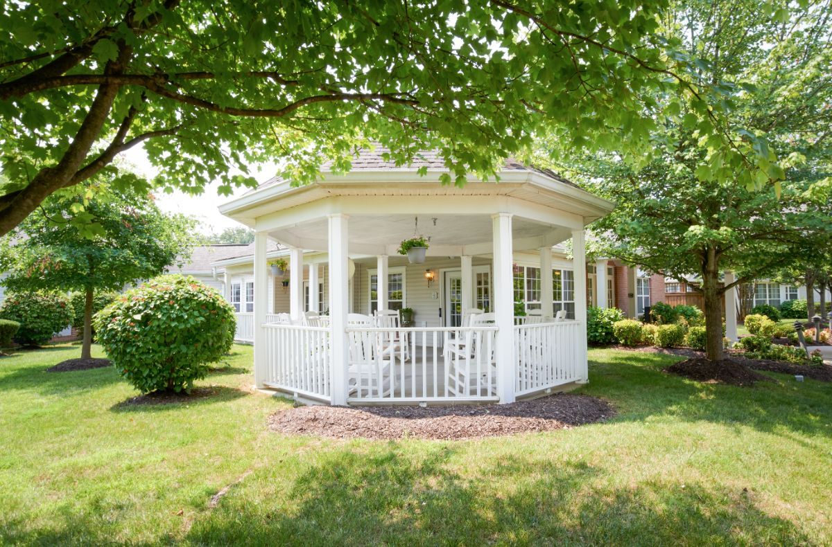 A white gazebo surrounded by a lush garden and trees.