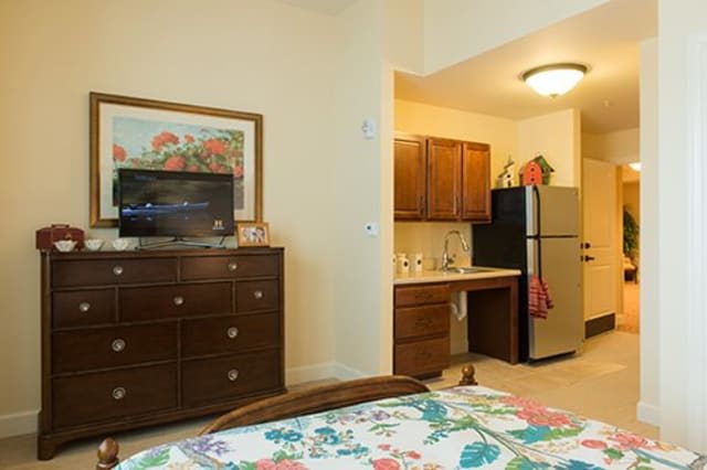 A cozy apartment interior featuring a small kitchen, wooden furniture, and a television.