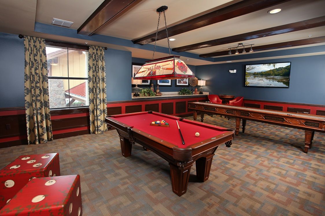 A cozy game room featuring a red-felt pool table and comfortable seating.