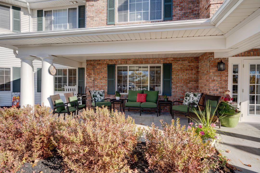 A cozy porch with outdoor seating in front of a brick house.