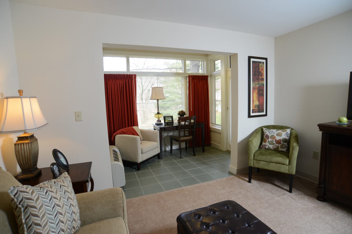 A cozy living room featuring a seating area with a sofa, chairs, and a small table by the window.
