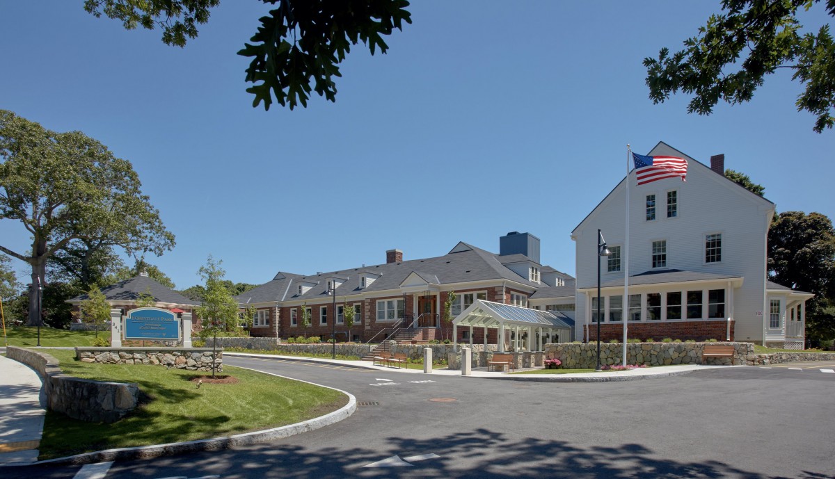 A hospital building with an American flag flying in front on a clear day.
