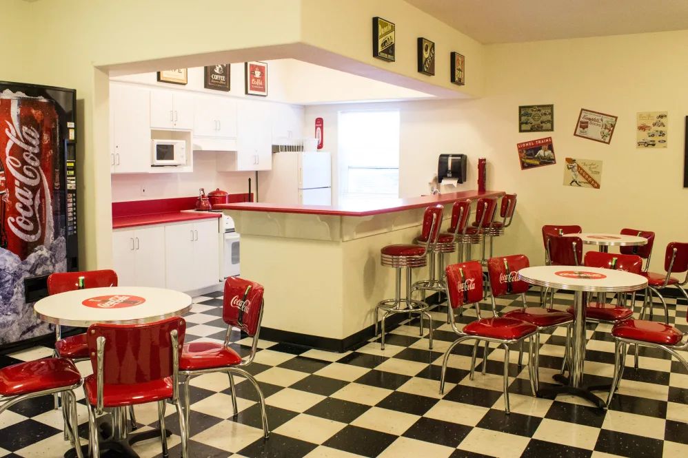 A retro-style diner with red seating, nostalgic decor, and a black and white checkered floor.