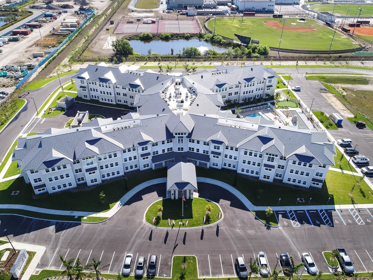 Aerial view of a large building complex with surrounding parking lot and roads.