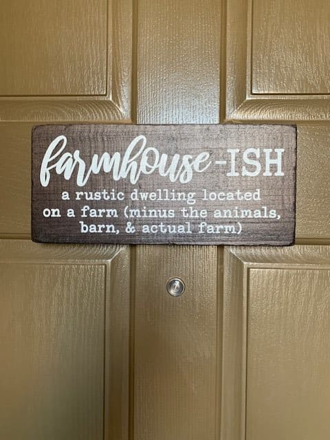 A humorous wooden sign that reads 'farmhouse-ISH: a rustic dwelling located on a farm (minus the animals, barn, & actual farm)'.