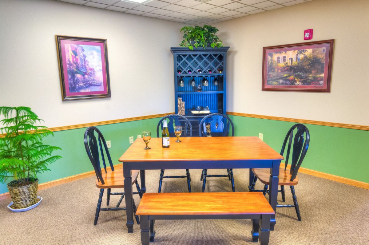 A cozy dining room with a wooden table set, blue hutch, and decorative paintings.