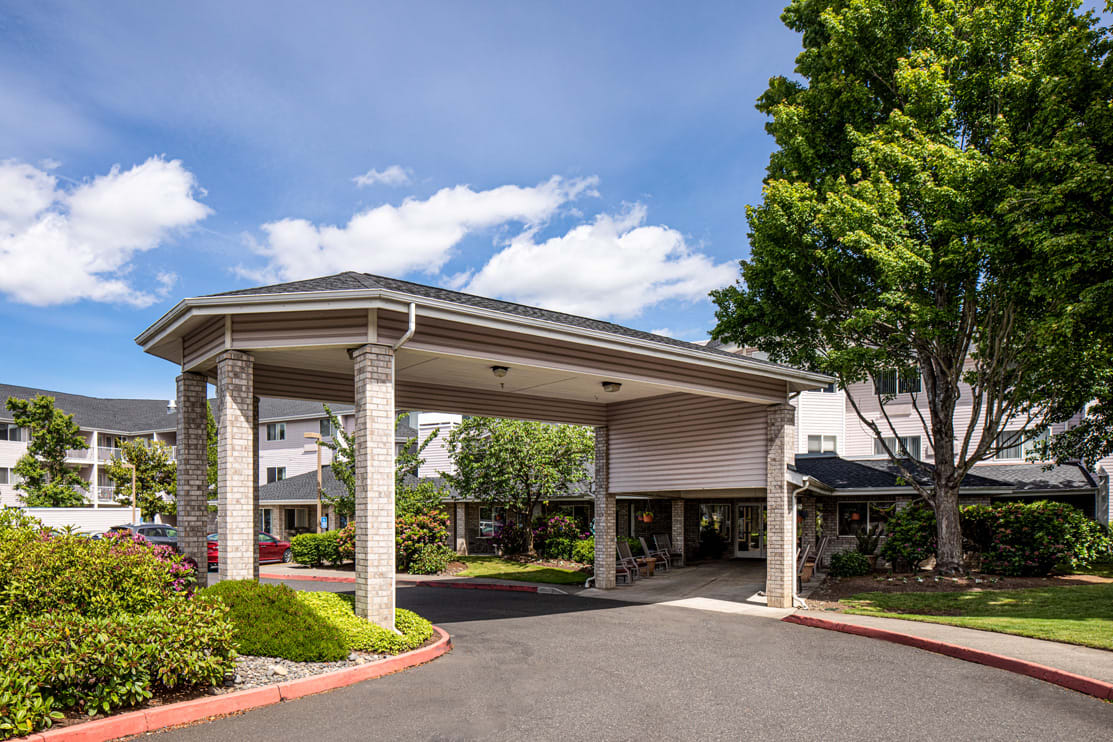 A hotel entrance with a covered driveway surrounded by trees and landscaping.