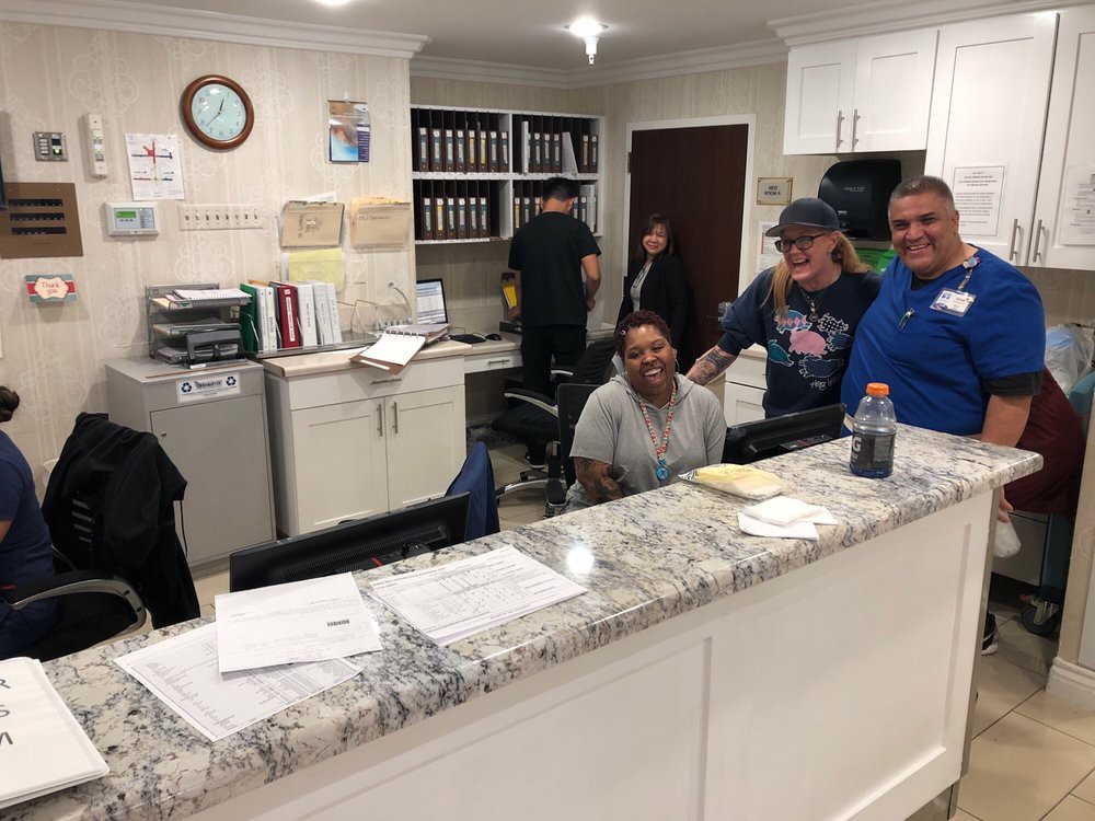 A group of people smiling at the reception desk in an office setting.