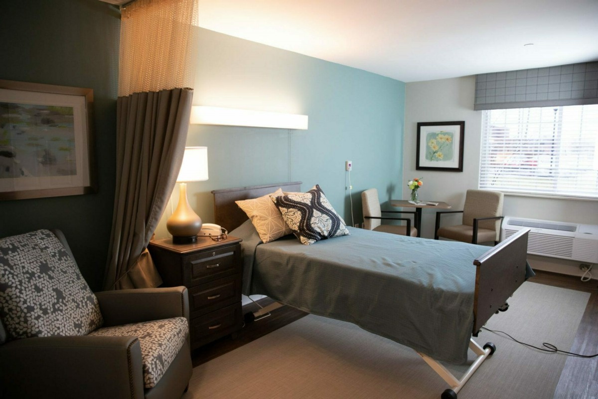 A modern and well-decorated bedroom with a single bed, comfortable seating, and ambient lighting.