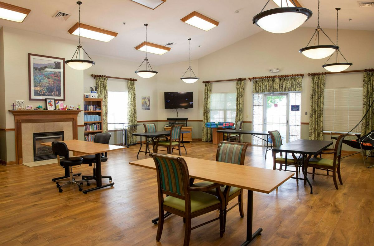 A well-lit communal room with tables, chairs, and a television.