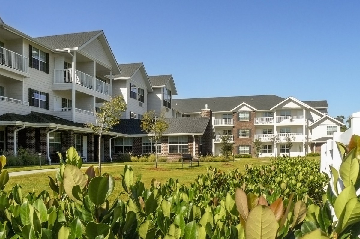 A view of a modern residential building surrounded by lush greenery on a clear day.