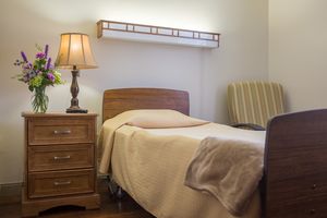A cozy bedroom with a single bed, nightstand, and lamp.