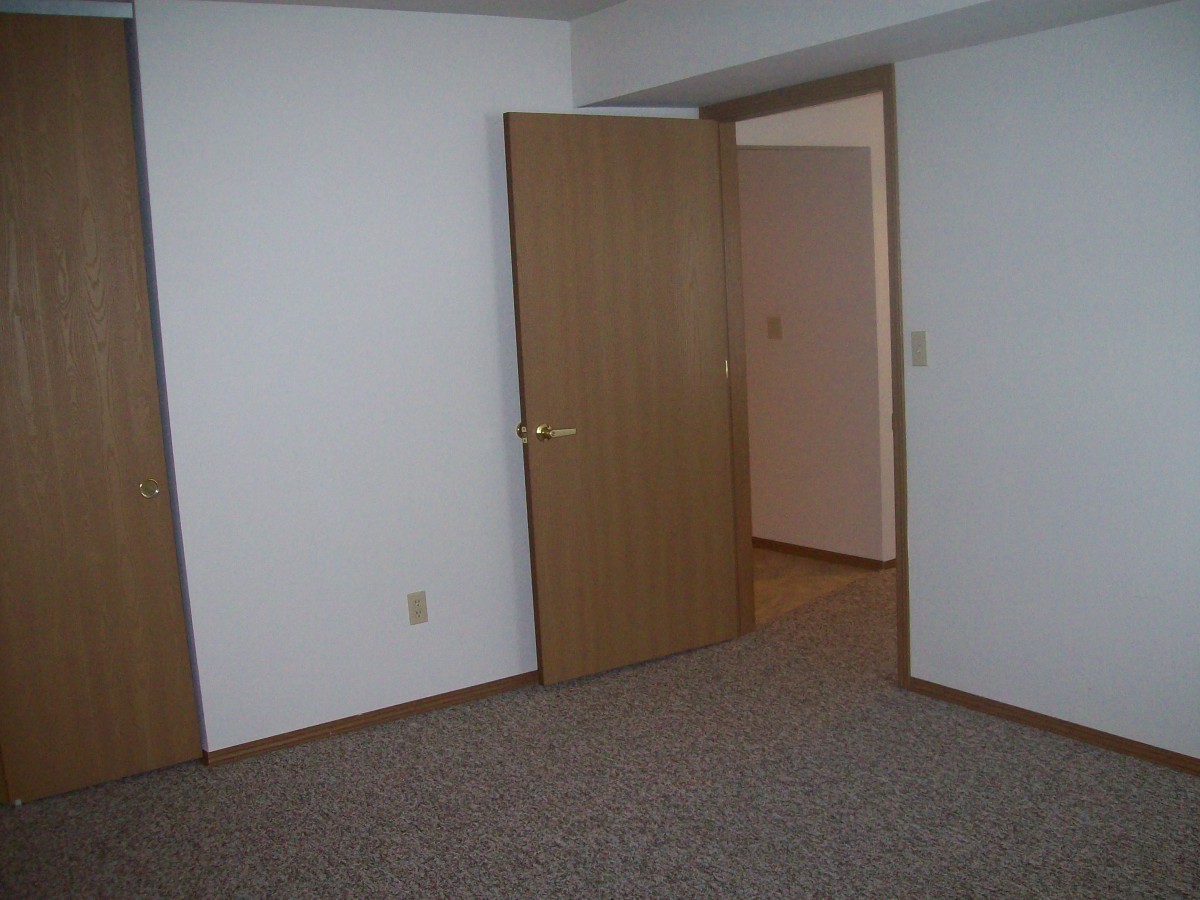 An empty room with carpet flooring and open doors.