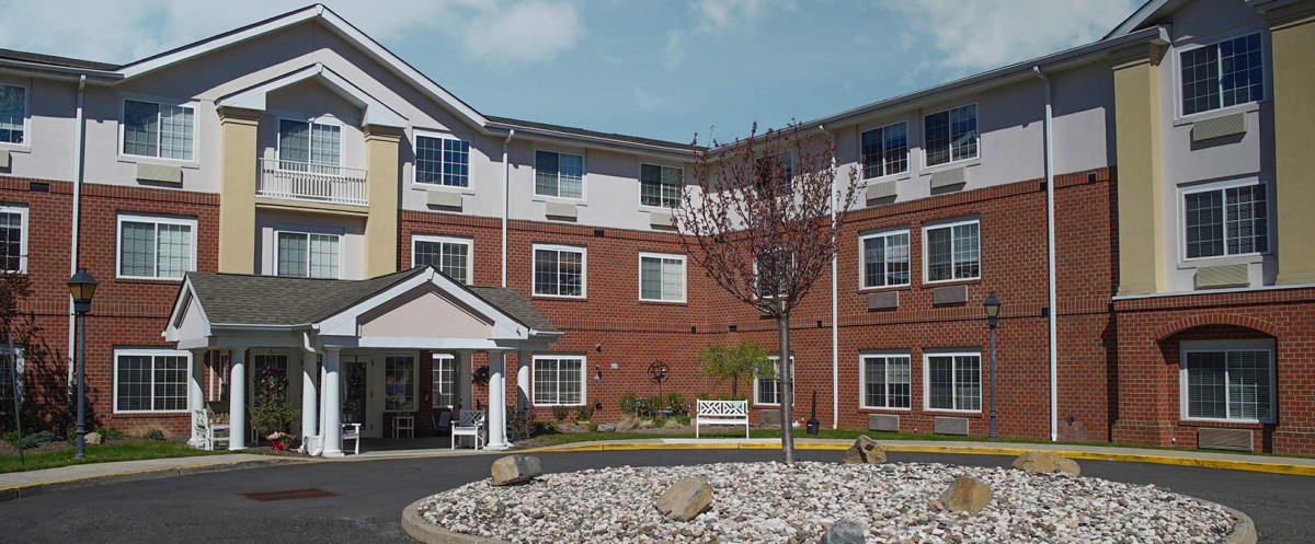 A multi-story brick and siding residential building with landscaped surroundings.