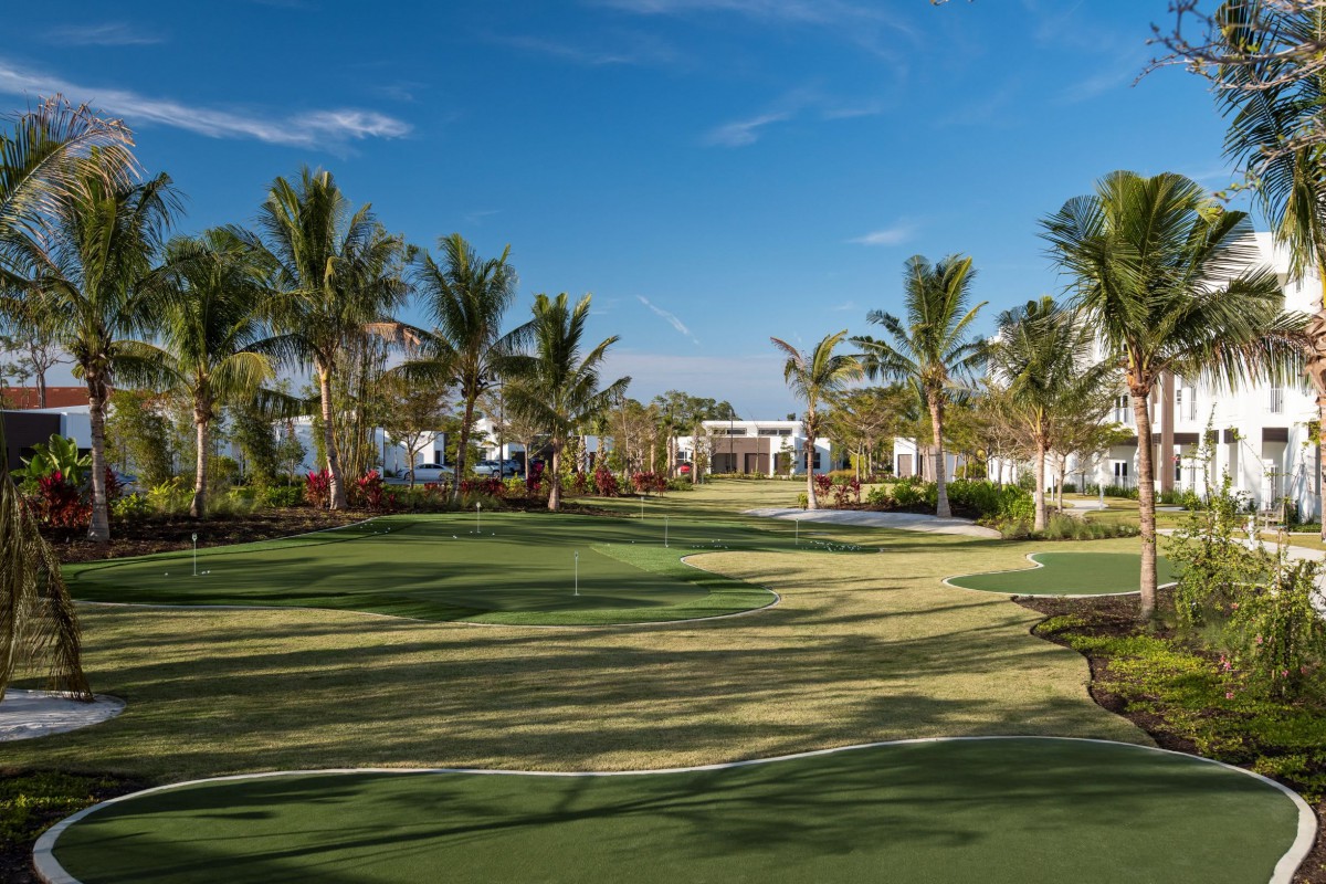 A scenic view of a tropical golf course surrounded by palm trees under a clear blue sky.