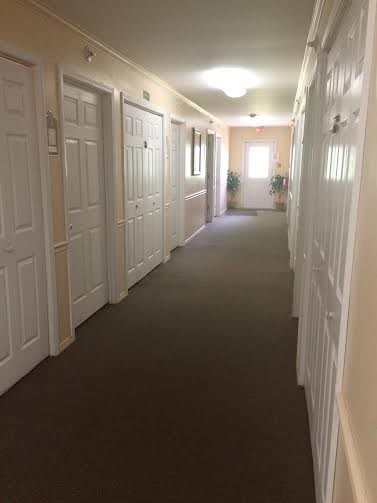 A well-lit indoor hallway lined with white doors.
