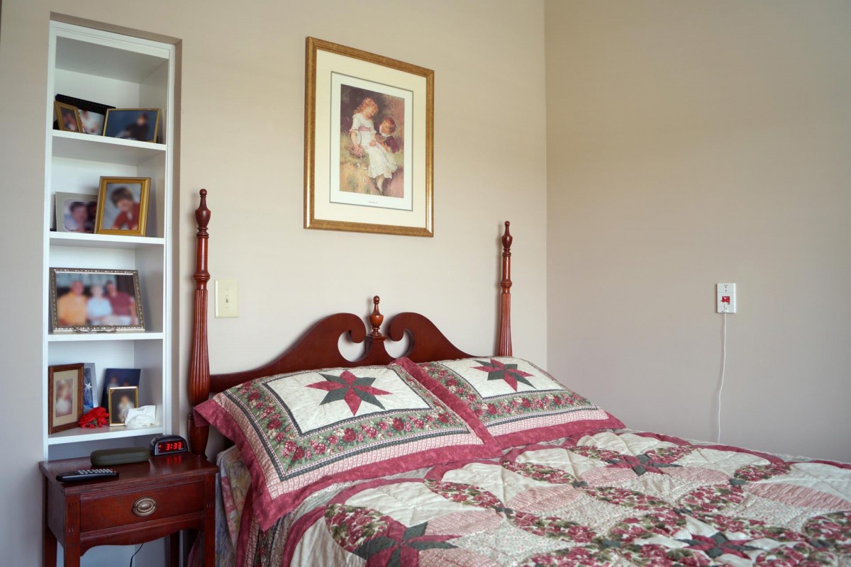 A cozy bedroom featuring a quilted bed with matching pillows and a decorative framed artwork above the headboard.