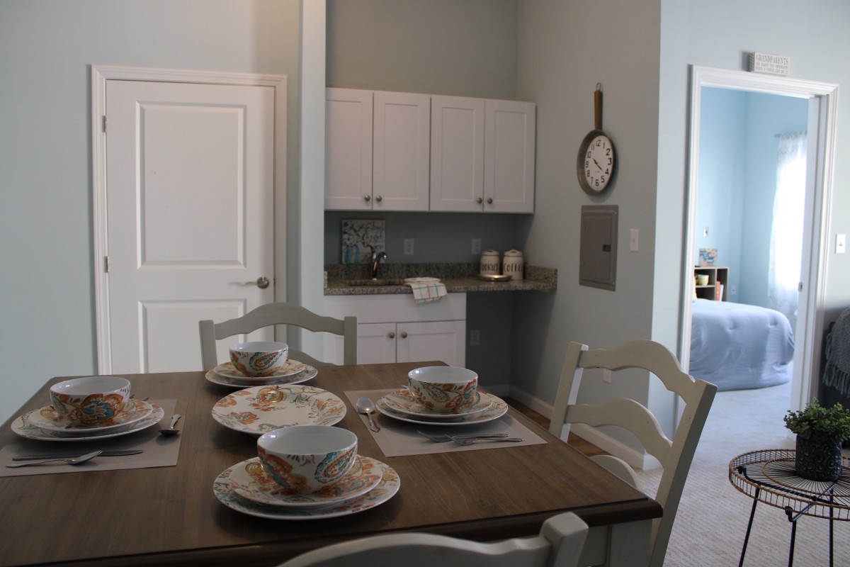 A cozy dining area with a table set for four, adjacent to a small kitchenette.