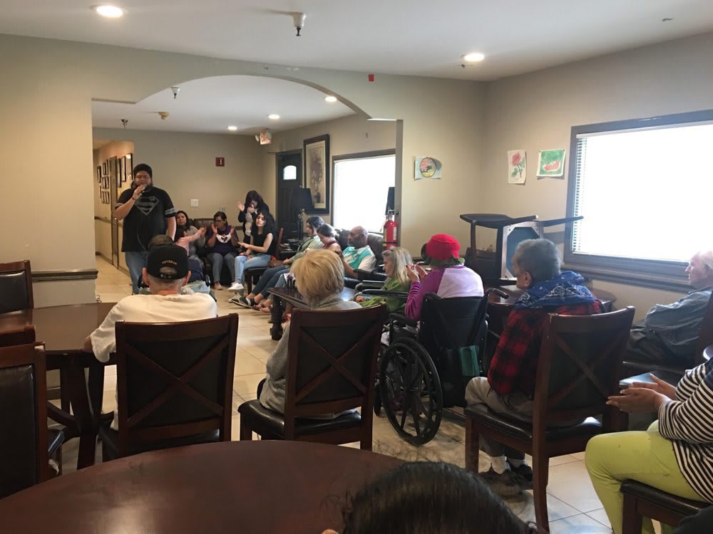 A group of people gathered indoors, listening to a speaker.